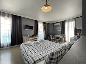 Une chambre d’hôtel moderne équipée d’un grand lit, d’un bureau avec un ordinateur, d’une chaise et d’un canapé.