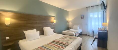Quarto de hotel com uma cama grande, uma escrivaninha e uma cadeira.
