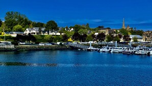 A marina with boats docked, a stone wall, and buildings in the background. - Hotel du Trégor (Treguier)