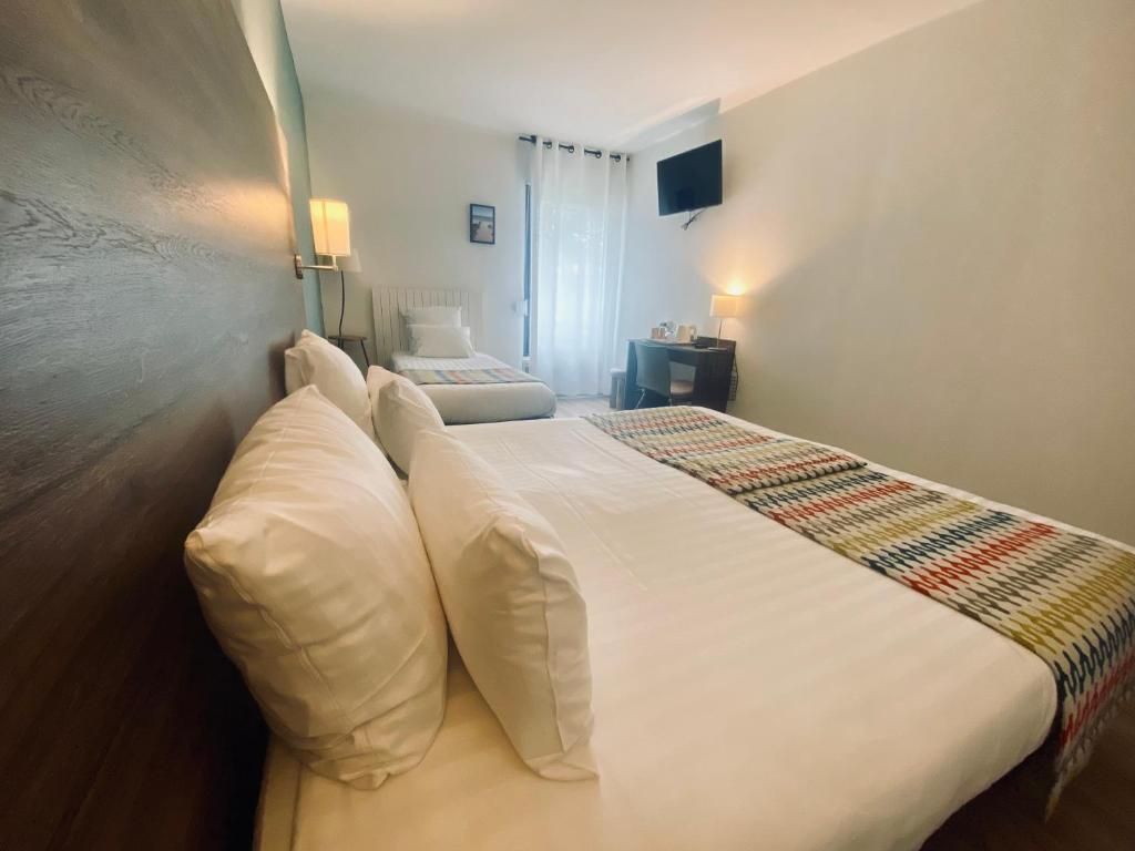 Habitación de hotel con cama, escritorio, silla, televisión y ventana con cortinas.