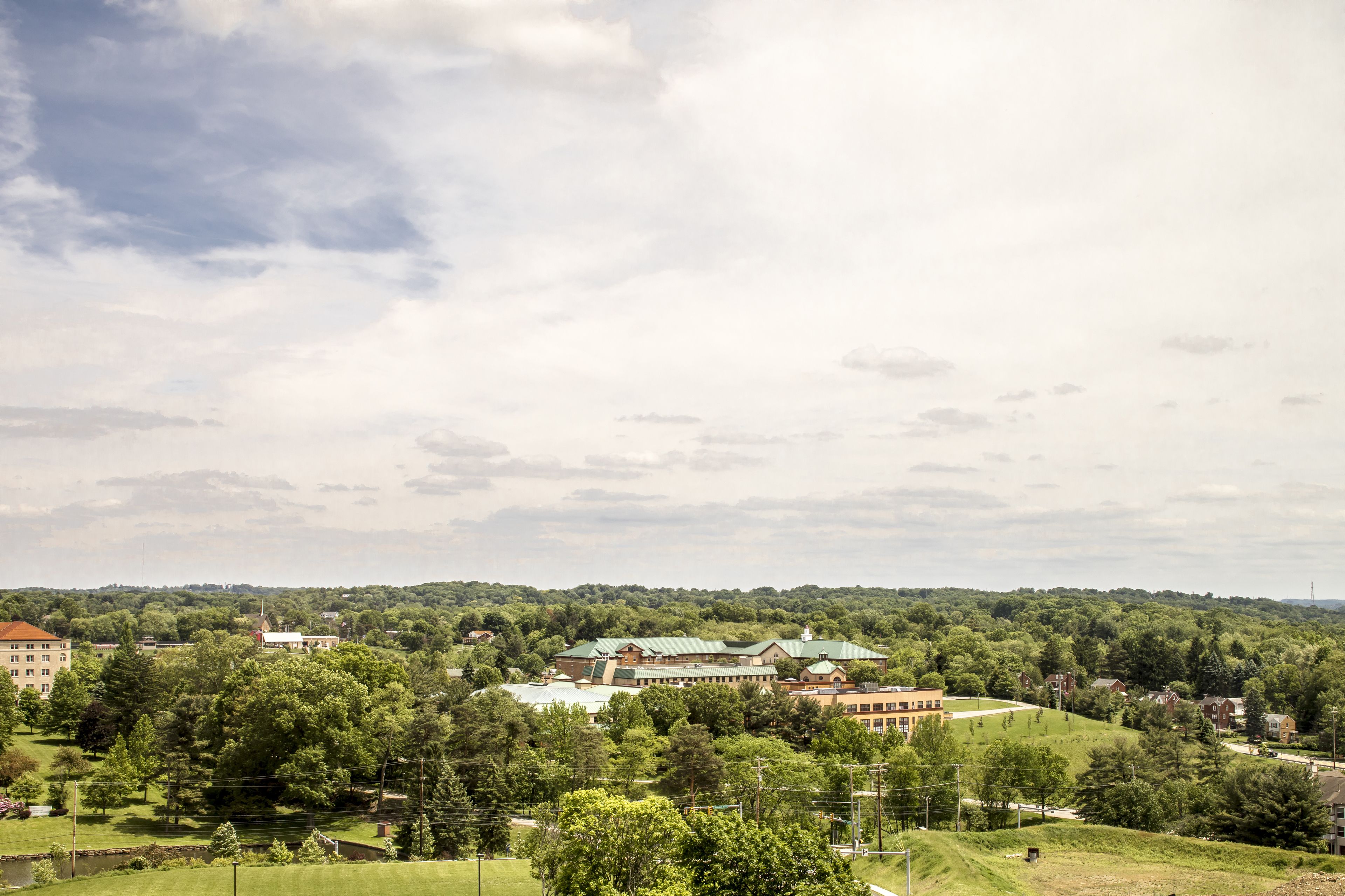 A large building complex surrounded by lush greenery, with multiple buildings and a prominent central structure.
