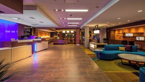Un moderno vestíbulo de hotel con mostrador de recepción, zona de estar y un bar.