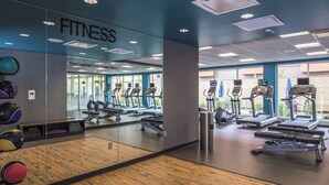 Un gimnasio con equipamiento de ejercicio, un espejo y suelo de madera.
