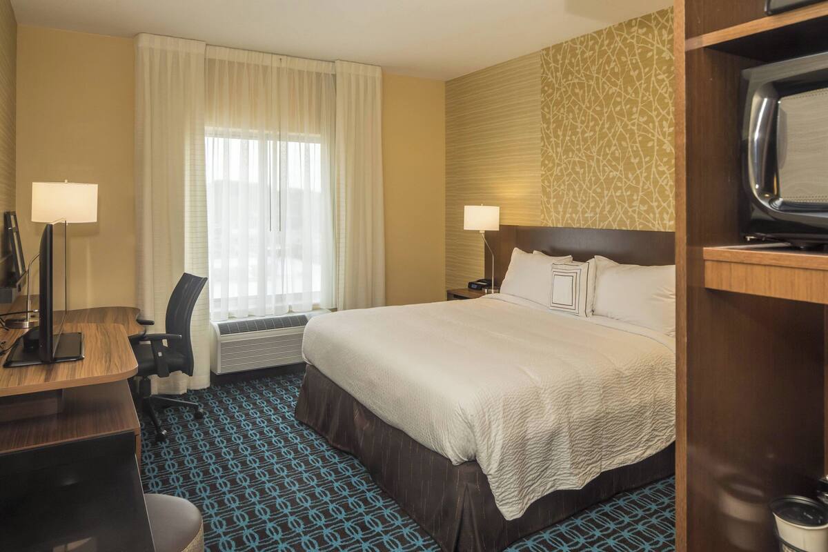 Una habitación de hotel con cama, escritorio, silla y televisión.