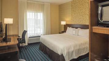 A hotel room with a bed, desk, chair, and a television.