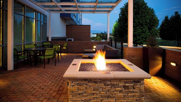 A patio area with a fire feature, outdoor seating, and a glass-enclosed structure. - SpringHill Suites by Marriott Kansas City Lenexa City Center (Lenexa)