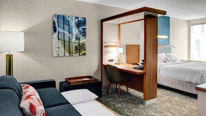 A hotel room with a sofa, a desk, a bed, a mirror, and a painting on the wall. - SpringHill Suites by Marriott Kansas City Lenexa City Center (Lenexa)