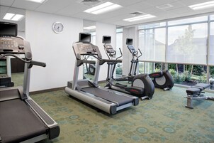 Un gimnasio con cintas de correr, elípticas y una banca.