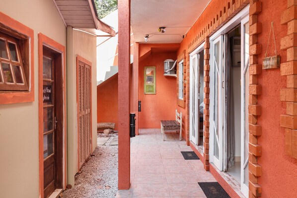 A narrow corridor with a bench, a door, and a window with shutters.