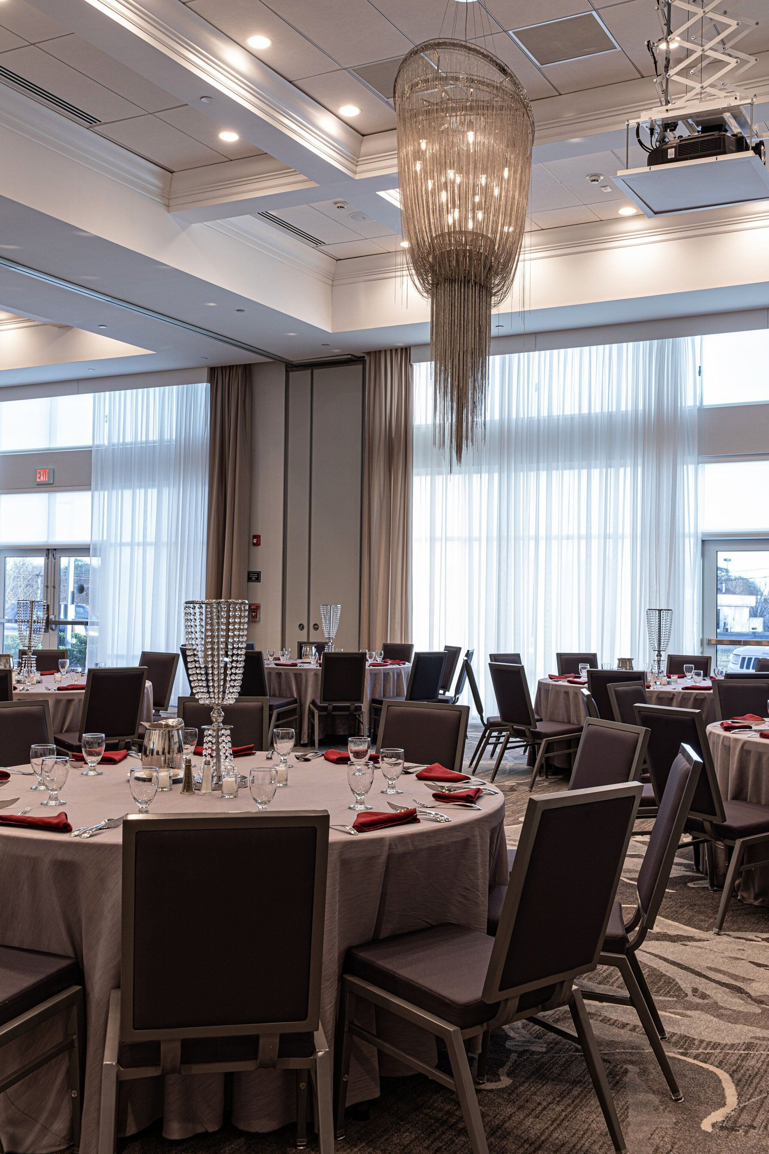 A conference room with round tables, chairs, and a large chandelier.