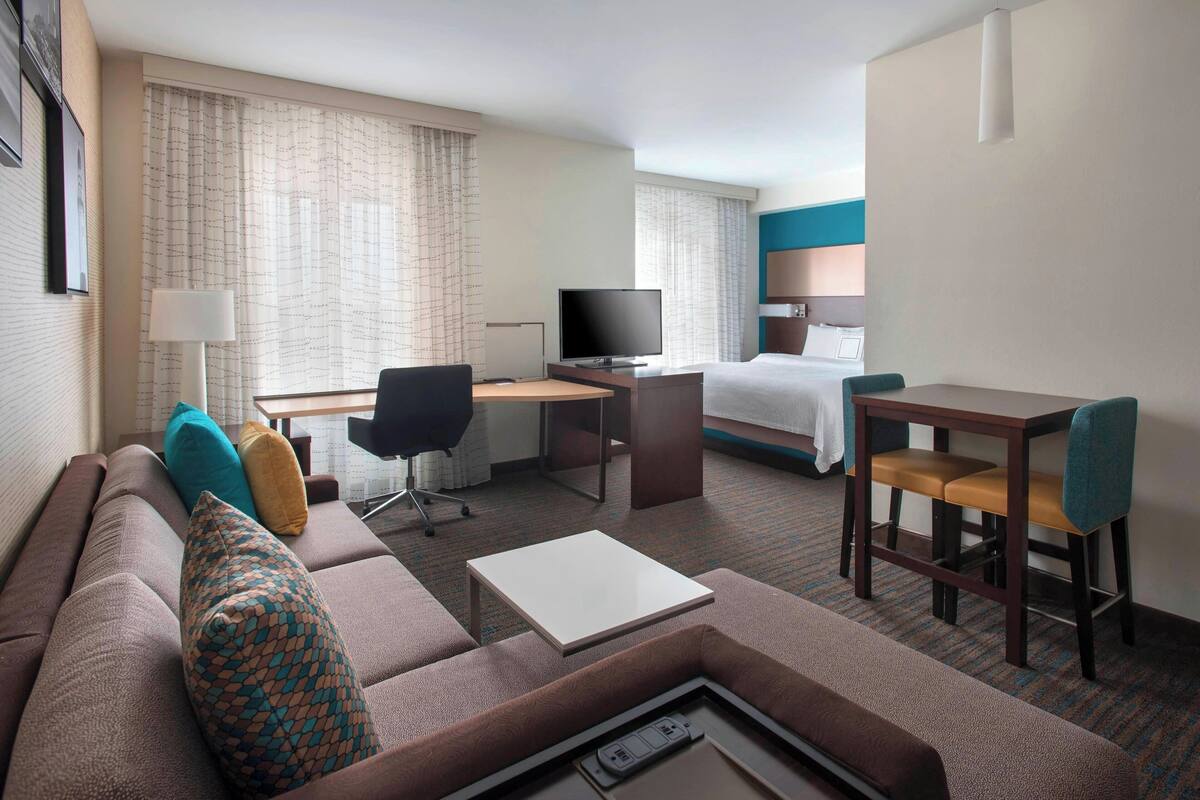 Une chambre d’hôtel avec un canapé, un bureau avec un ordinateur, un lit et une télévision.