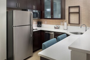 Una cocina moderna con electrodomésticos de acero inoxidable, armarios de madera oscura, un microondas y una cafetera.