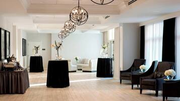 A spacious lobby with a high ceiling, a chandelier, a reception desk, and seating areas.