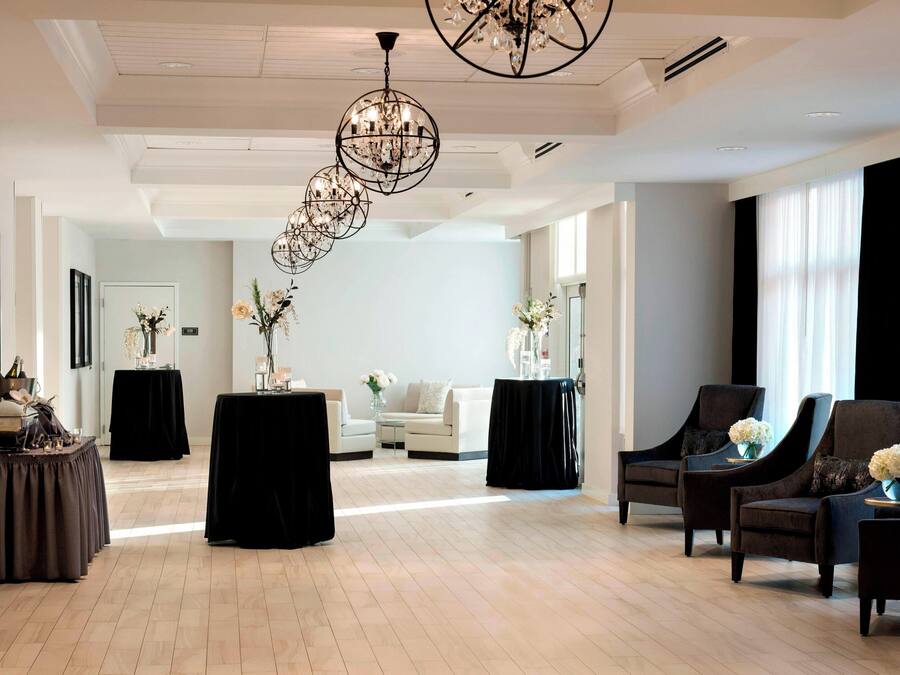 A spacious lobby with a high ceiling, a chandelier, a reception desk, and seating areas.