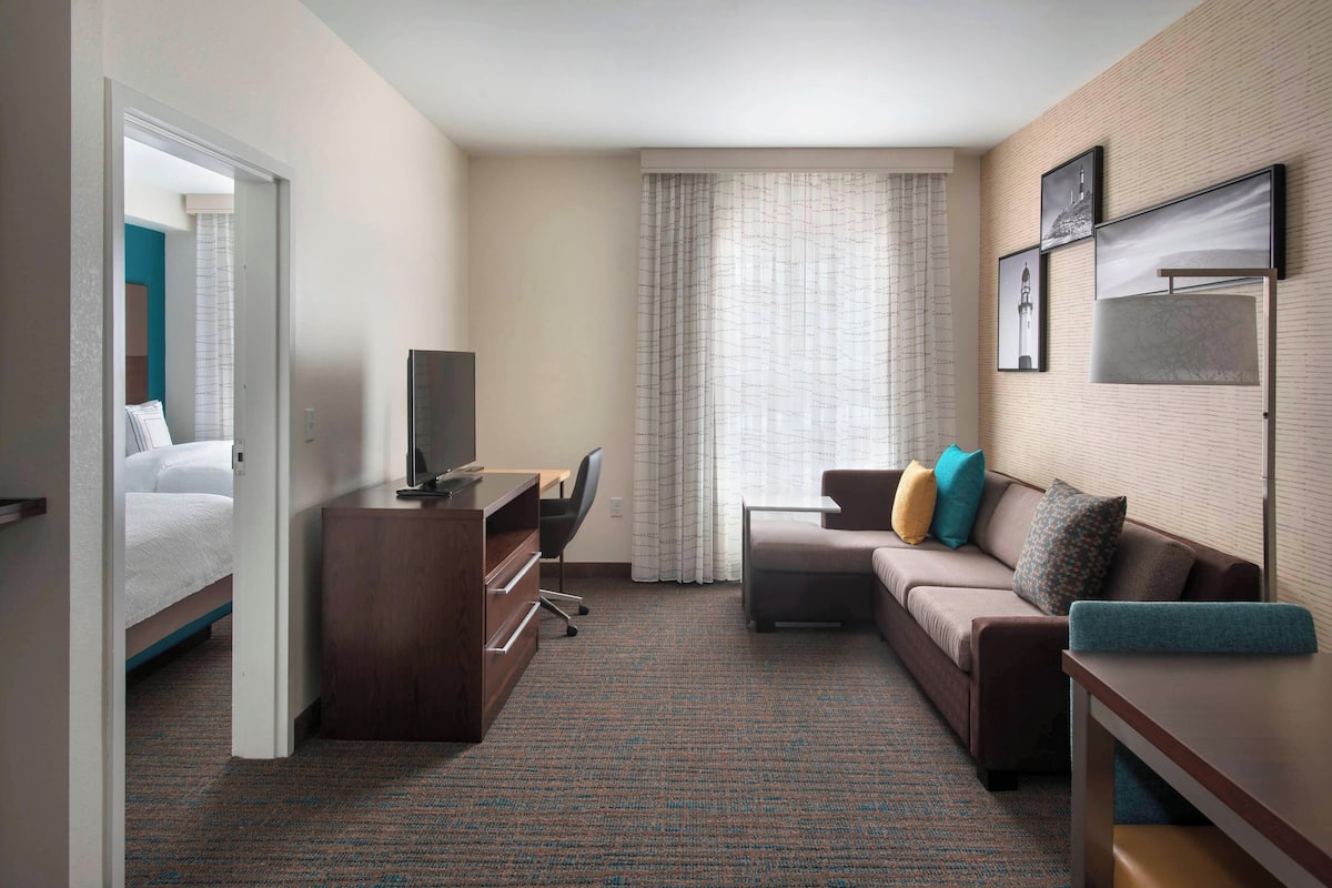Une chambre d’hôtel avec un lit, un bureau, un canapé et une télévision.