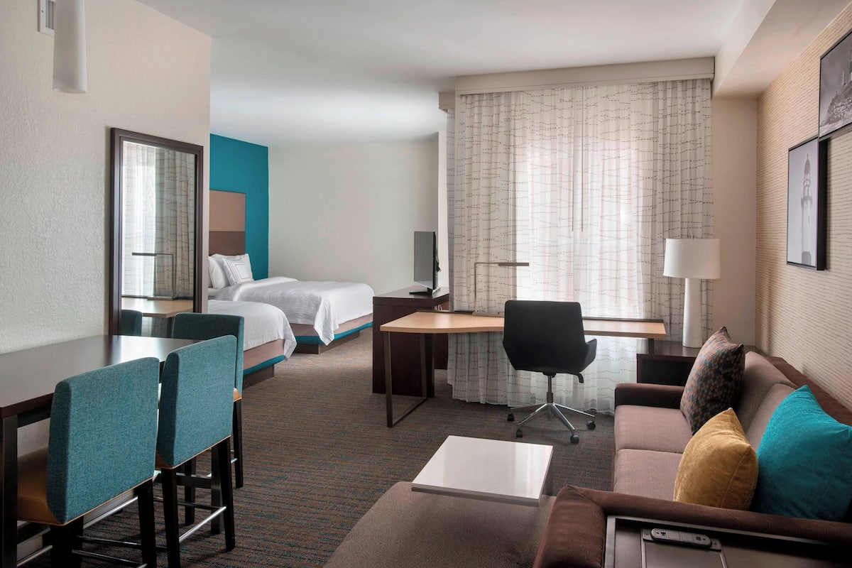Une chambre d’hôtel équipée d’un lit, d’un bureau, d’une chaise, d’un canapé et d’une télévision.