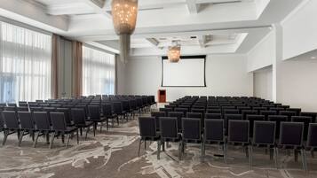 A conference room with rows of chairs, a projector screen, and a podium.