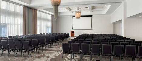 A conference room with rows of chairs, a projector screen, and a podium.