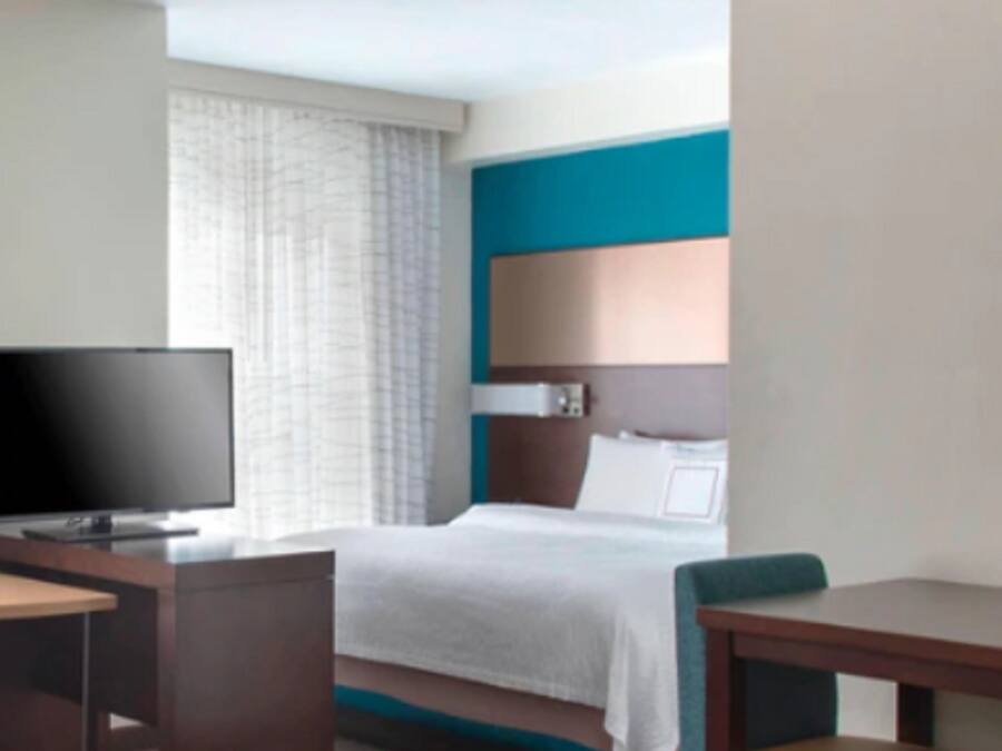 A hotel room with a bed, a TV, a desk, and a chair.
