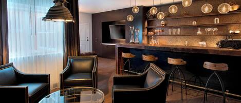 A modern bar area with a round glass table, leather chairs, and a bar counter with stools.