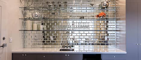 A kitchen with a tiled backsplash, a stainless steel sink, and modern cabinetry.