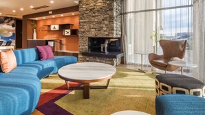 A modern living room with a stone fireplace, a blue sofa, a round coffee table, and a leather armchair. - Fairfield Inn and Suites by Marriott Moses Lake (Moses Lake)