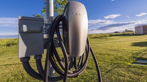 A Tesla charging station with multiple cables connected to it, set against a grassy field and a clear sky. - Fairfield Inn and Suites by Marriott Moses Lake (Moses Lake)