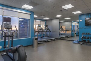 A gym with treadmills, a stationary bike, and dumbbells.