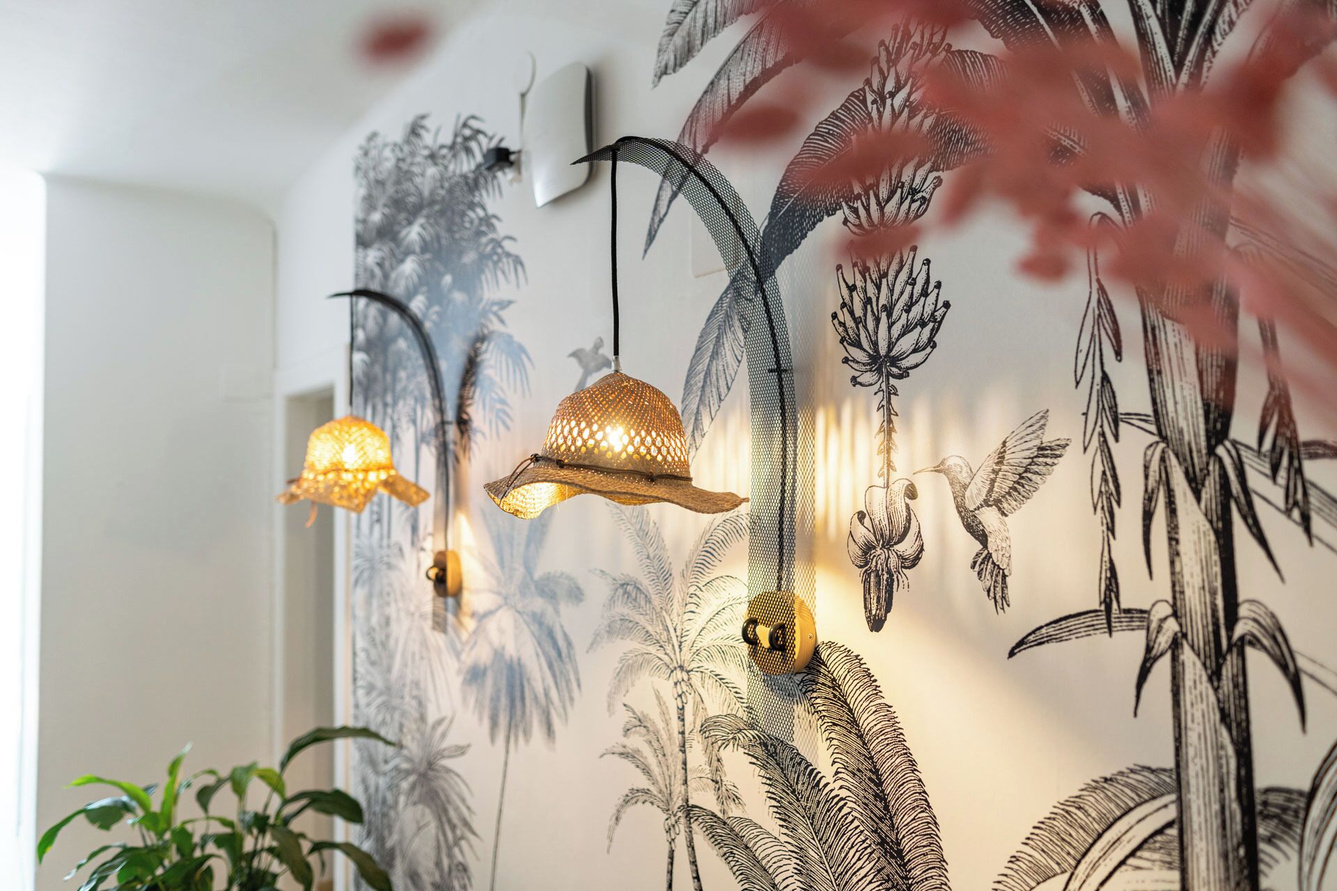 A wall with a tropical mural, two hanging lamps, and a light switch.