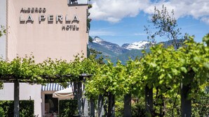 Das Hotel Albergo La Perla mit Blick auf schneebedeckte Berge im Hintergrund.