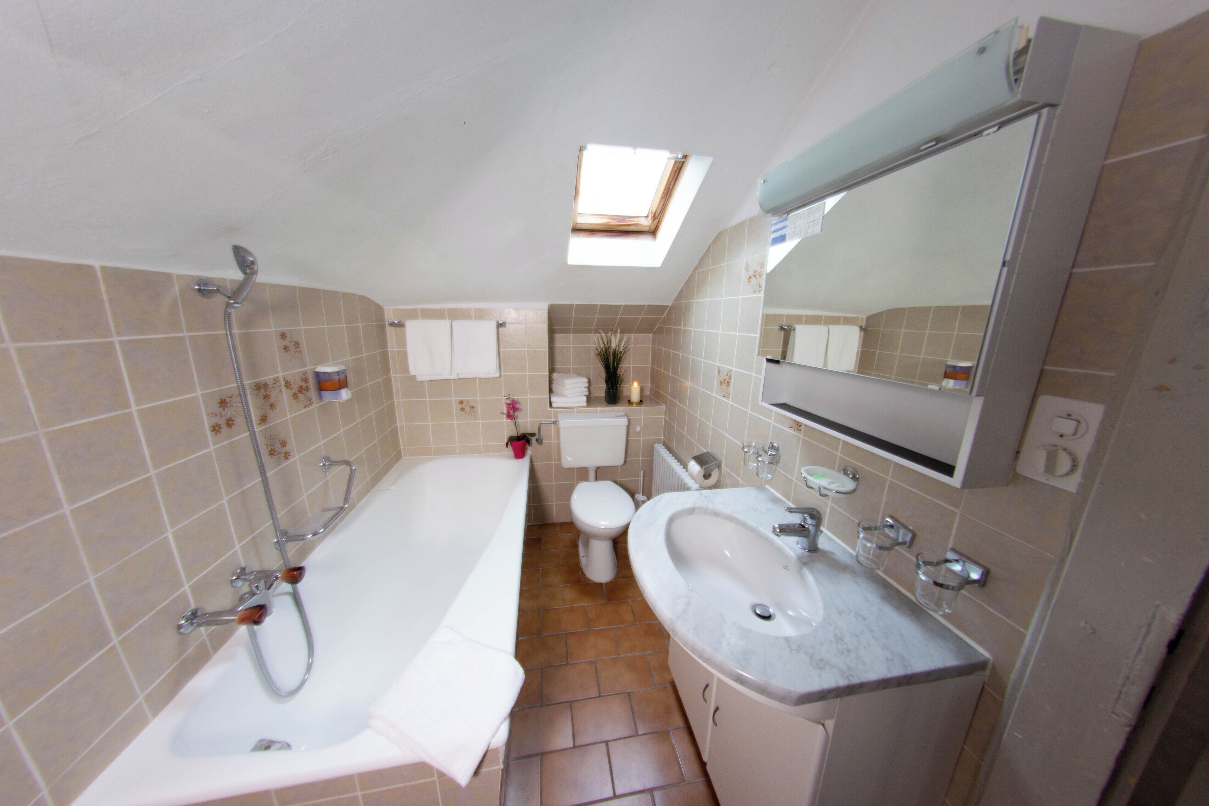 Ein Badezimmer mit einer Badewanne, einem Waschbecken, einer Toilette und einem Oberlicht.