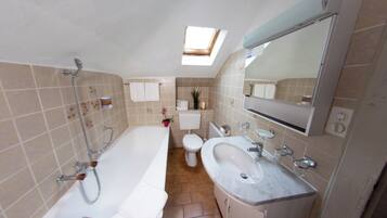 Ein Badezimmer mit einer Badewanne, einem Waschbecken, einer Toilette und einem Oberlicht.