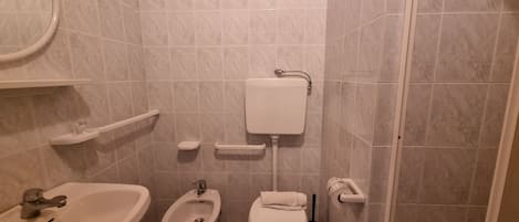 A bathroom with a sink, bidet, toilet, and a mirror.