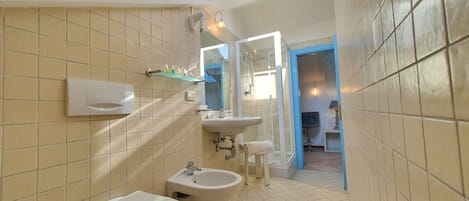 A bathroom with a skylight, a bidet, a toilet, and a sink.
