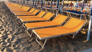 Une rangée de chaises longues sur une plage de sable.