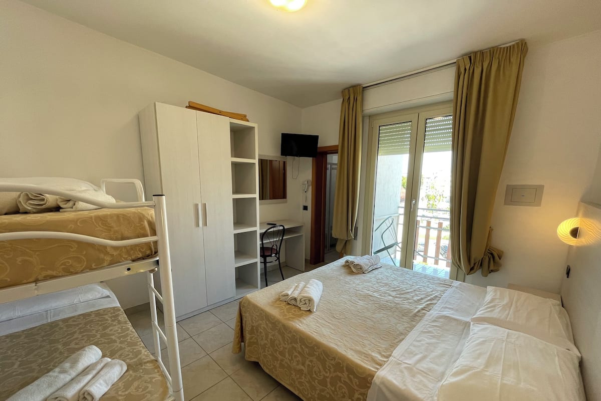 Hotellihuone, jossa on kaksi sänkyä, vaatekaappi, työpöytä ja parveke.