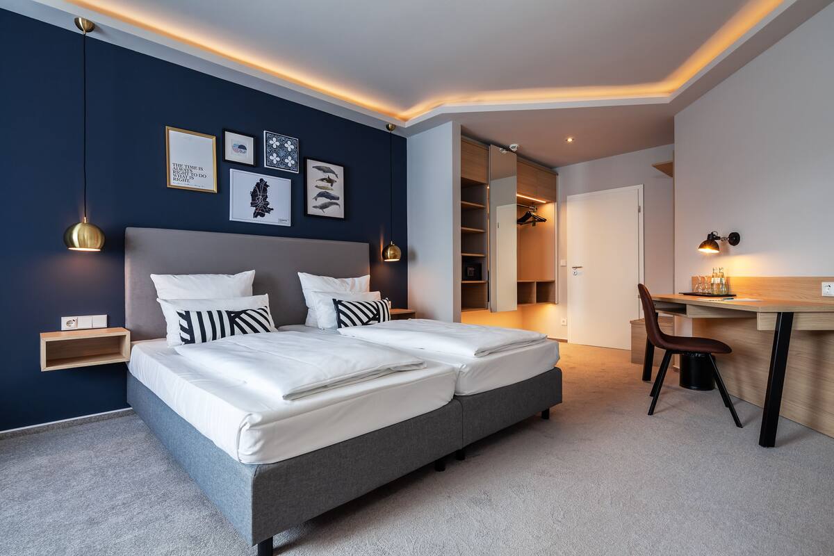 Un dormitorio moderno con una cama doble, mesitas de noche, un escritorio y una silla.