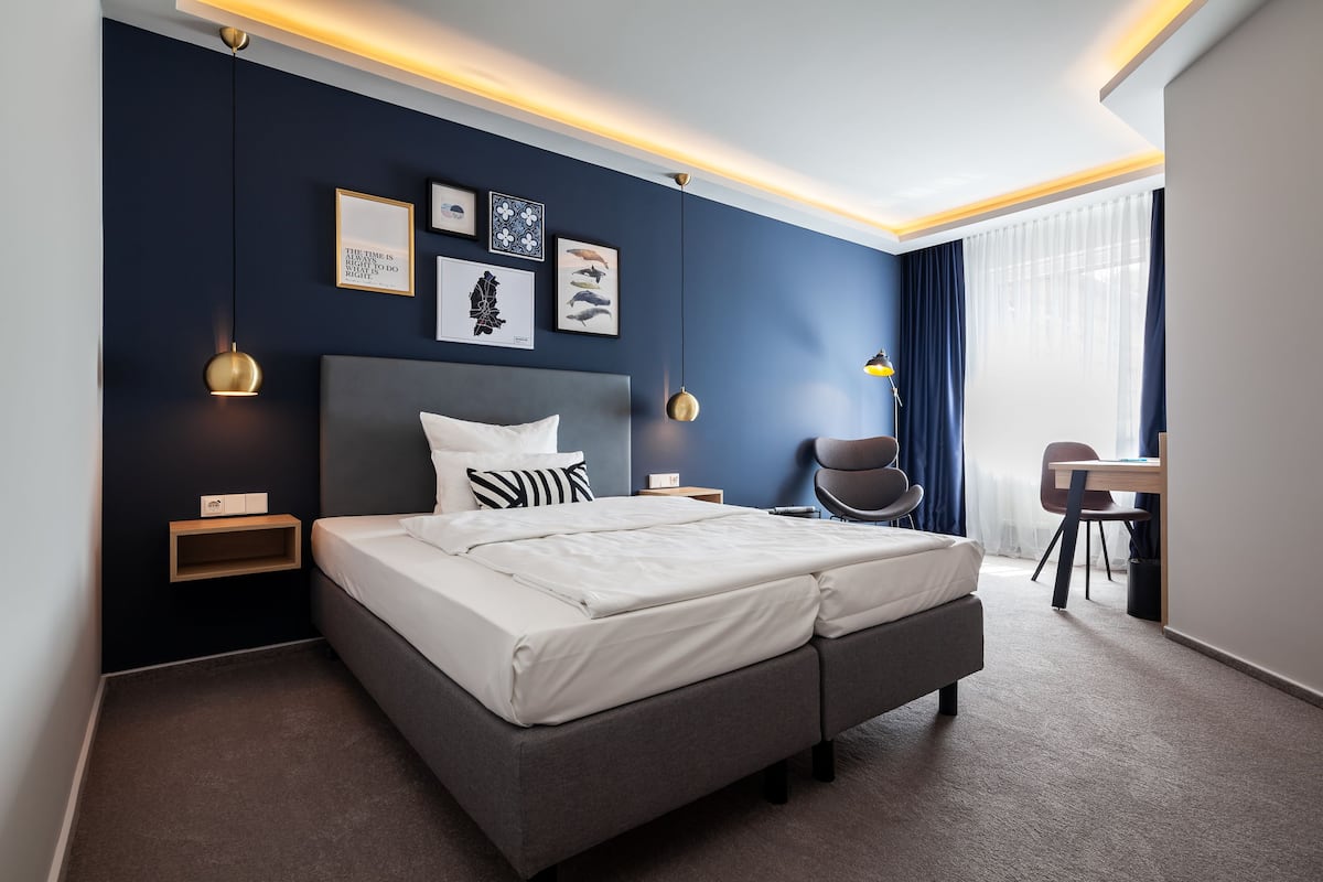Una habitación de hotel moderna con una cama grande, mesitas de noche, un escritorio y una silla.