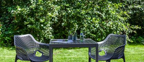 Una mesa con dos sillas en un jardín.