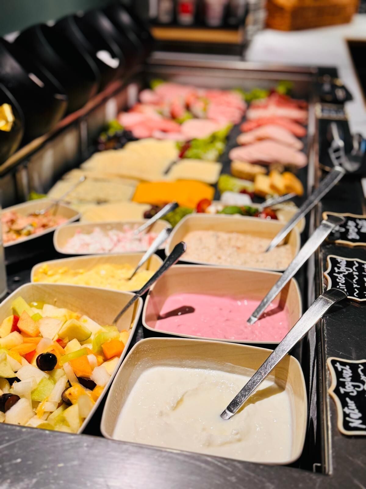 Ein reichhaltiges Buffet mit verschiedenen Speisen, darunter Obst, Salate und unterschiedliche Dip-Sorten.