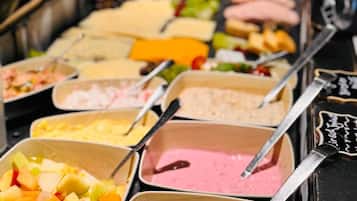 A buffet with various food options including fruits, salads, and different types of dips.