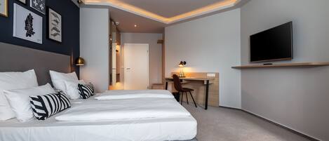 Una habitación de hotel moderna con una cama grande, un escritorio y un televisor.
