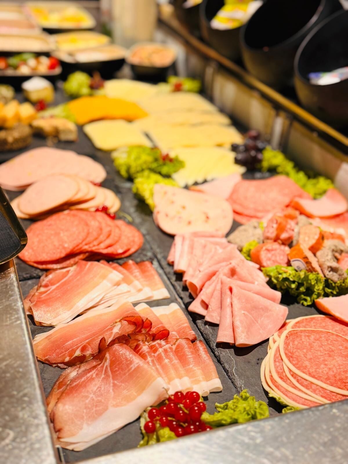 A variety of meats and cheeses on a display counter.