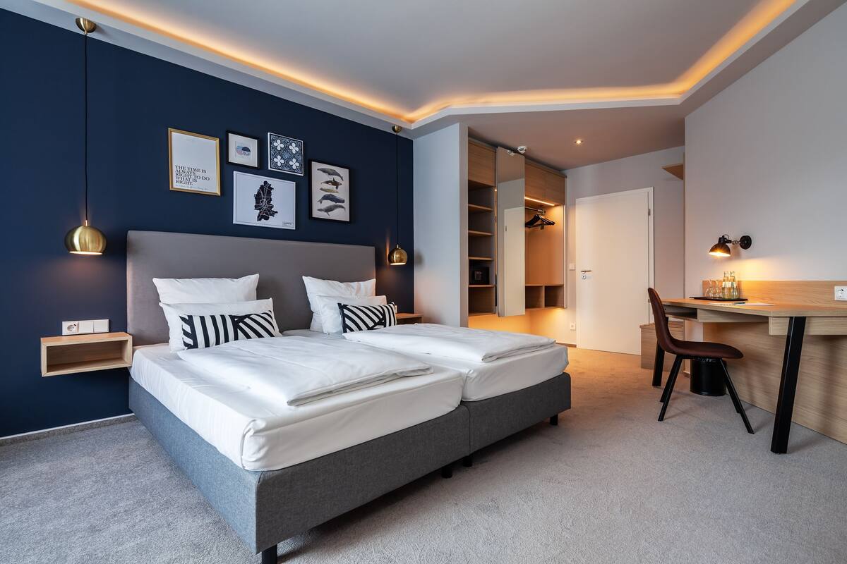 Un dormitorio moderno con una cama doble, mesitas de noche, un escritorio y una silla.