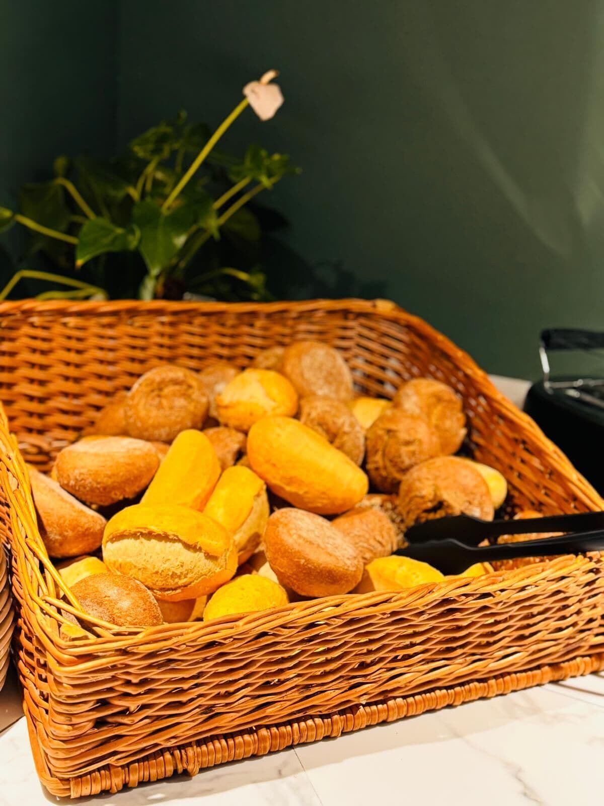 Een rieten mand gevuld met verschillende soorten brood, geplaatst op een marmeren oppervlak.