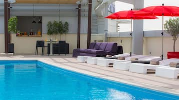 Alberca al aire libre, sombrillas en la alberca y camastros