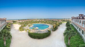 Un complexe hôtelier doté d’une piscine centrale, entouré de palmiers et offrant une vue dégagée sur l’océan.