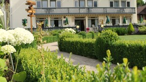 A hotel with a garden pathway, neatly trimmed hedges, and outdoor seating. - Hotel Bemelmans (Schin op Geul)