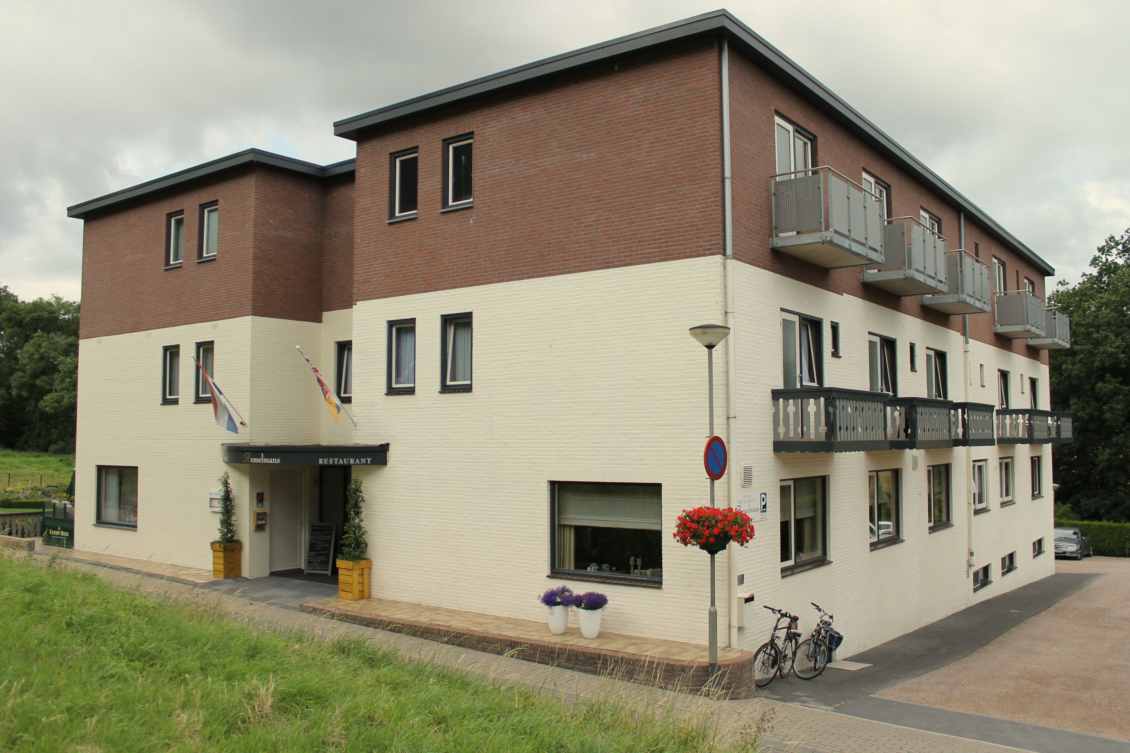 Ein zweistöckiges Gebäude mit Restaurant im Erdgeschoss, Balkon im zweiten Stock und einem Parkplatzschild.