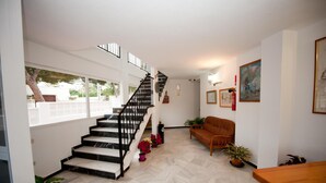 Un interior moderno con una escalera, un sofá y plantas en macetas.